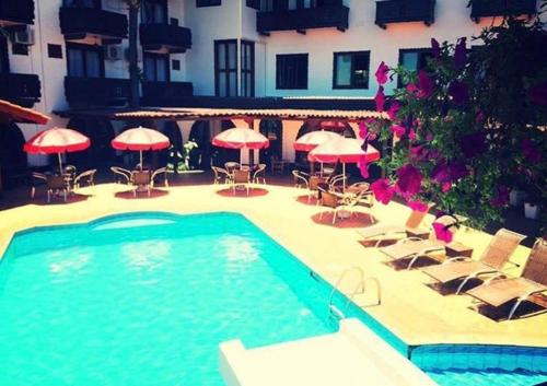a swimming pool with chairs and tables and umbrellas at Hotel Tirol in Treze Tílias