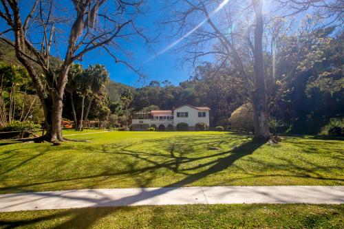 a house in the middle of a green yard with trees at Saison Resort & Spa in Itaipava
