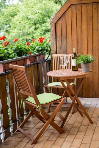 a table and chair on a deck with a bottle of wine at Haus Rose in Allensbach