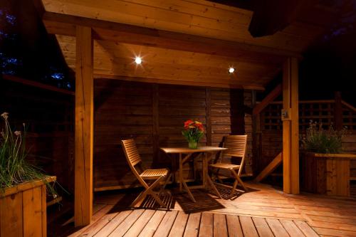 a wooden patio with a table and chairs on a deck at Cedar House Restaurant & Chalets in Golden