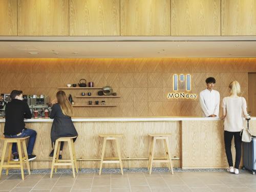 a group of people standing at a counter in a restaurant at hotel MONday Premium TOYOSU in Tokyo
