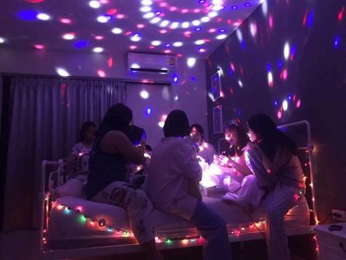 un grupo de personas sentadas en las camas en una habitación con luces en Apartment Khunpa, en Lamai