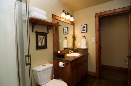 a bathroom with a toilet and a sink and a mirror at Cedar House Restaurant & Chalets in Golden