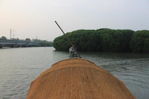 a man sitting on the end of a pier with a pole at Maleyam Homestay Riverside in Kozhikode