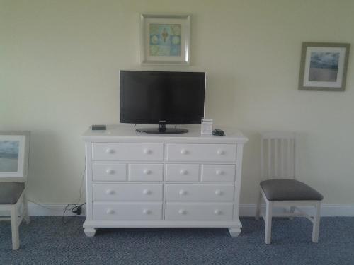 a white dresser with a television on top of it at Surf & Sand Beach Motel in South Yarmouth