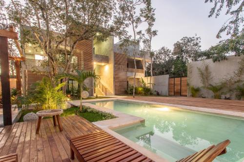 a swimming pool with a wooden deck and a house at Panacea Condo Tulum in Tulum