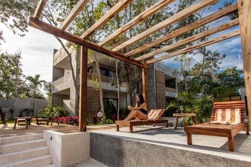 a woman sitting on a porch of a house at Panacea Condo Tulum in Tulum