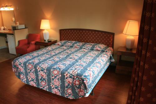 a hotel room with a bed and a red chair at Portland Value Inn & Suites in Portland