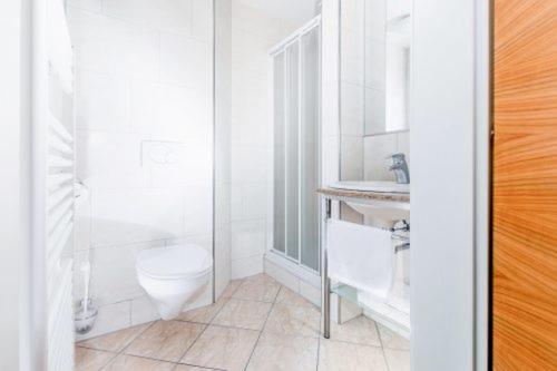 a white bathroom with a toilet and a sink at Rasthaus zum Dokl in Gleisdorf
