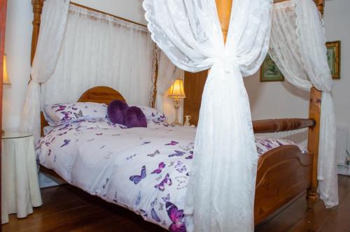 アンブルにあるWind Rose Cottageのベッドルーム(白いカーテン付きの天蓋付きベッド1台付)