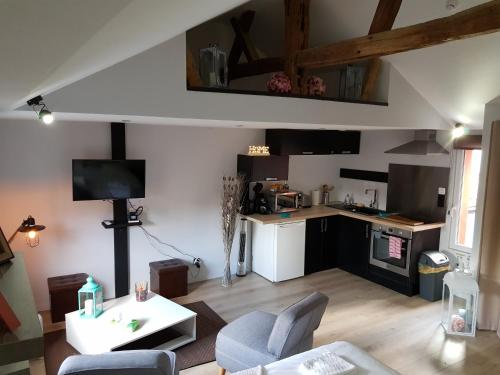 a living room with a table and a kitchen at Au detour de Gournay in Gournay-en-Bray