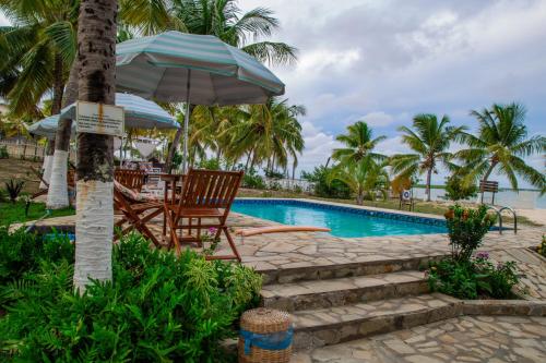 a swimming pool with a table and chairs and an umbrella at Pousada o Forte in Mangue Sêco