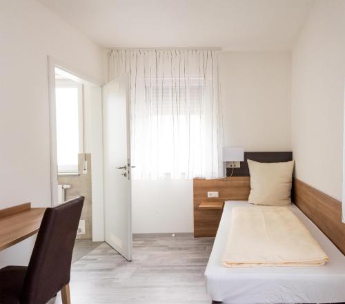 a bedroom with a bed and a desk and a window at Grüner Baum in Langenau