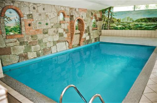 a large swimming pool in a room with a stone wall at Poziomka in Kujan