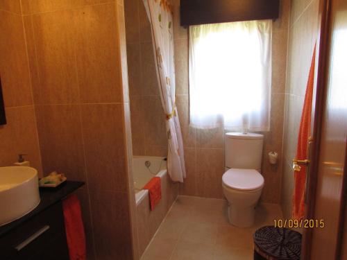 baño con aseo y lavabo y ventana en EL HOGARIN DE ARRIONDAS, en Arriondas