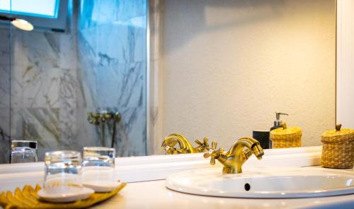 a bathroom sink with a gold faucet and a mirror at Elia Vama Veche (Adults Only) in Vama Veche