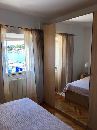 a bedroom with a mirror and a bed and a window at Apartments Barbaresko in Lumbarda