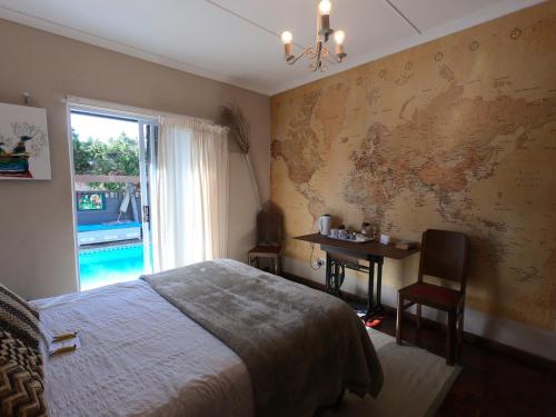 a bedroom with a bed and a desk and a map on the wall at Leo's Den in Fish hoek