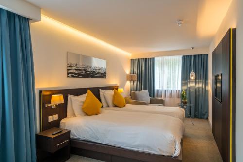 a hotel room with a large bed with yellow pillows at Pelican London Hotel and Residence in London