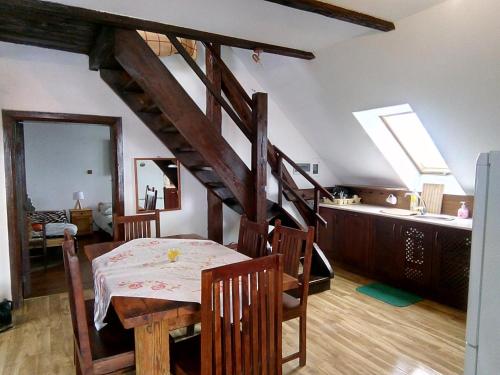 a dining room with a table and a wooden staircase at Apartament ogrodowy in Rydzewo