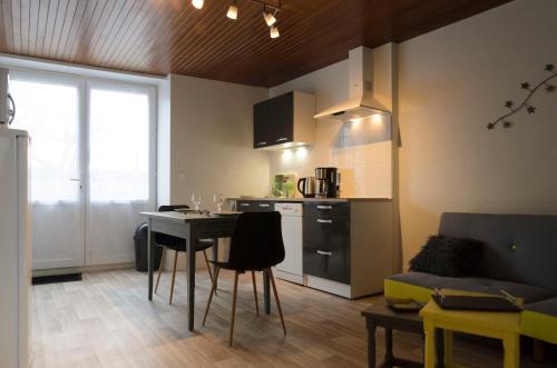 a kitchen and living room with a table and a couch at L'Orée des Lacs (Appartement n°3) in Pont-de-Poitte