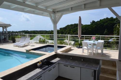 un patio con tavolo e sedie e una piscina di "Pépite" a Petit-Bourg