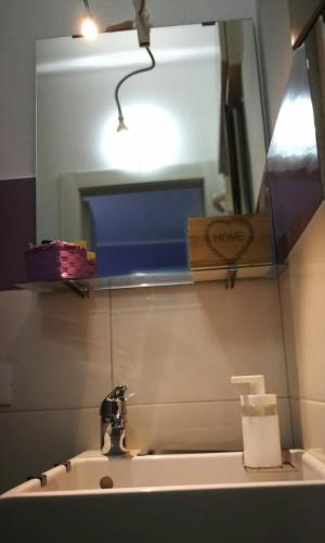 a bathroom sink with a light and a mirror at Dimora Fraula Guest House in Agrigento