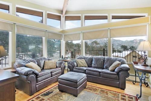 a living room with leather couches and large windows at Starlight In The Rockies in Estes Park