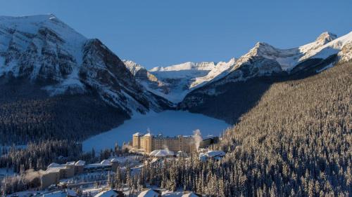 a resort in the middle of a mountain with a lake at Fairmont Château Lake Louise in Lake Louise