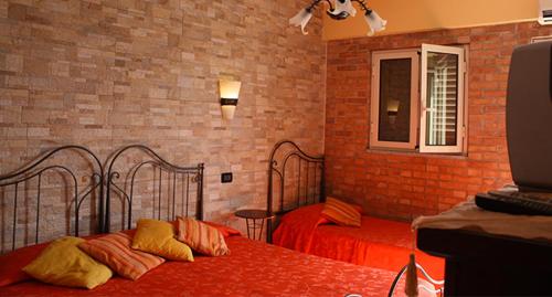 a bedroom with two beds and a brick wall at B&B Angolo Di Paradiso in Pellaro