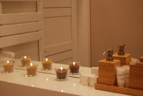four candles sitting on a counter in front of a mirror at 4 All Apart Hotel in Swarzędz