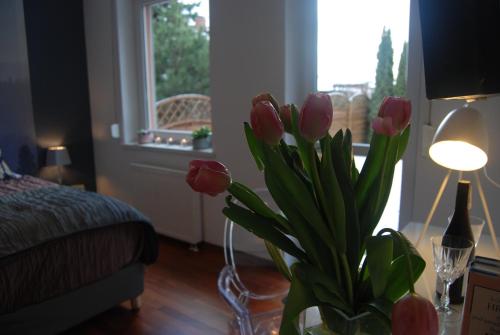 a vase of pink tulips in a room with a window at 4 All Apart Hotel in Swarzędz