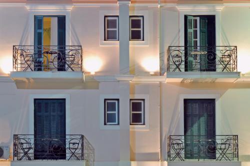 a white building with green doors and a balcony at Villa Ianthia in Galaxidhion