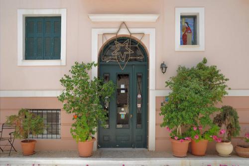 a green door on a pink building with potted plants at Villa Ianthia in Galaxidhion