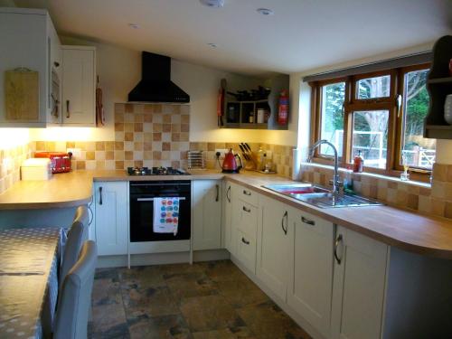 a kitchen with white cabinets and a sink at The Old Cowstall in Somerton