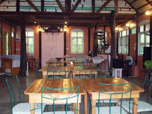 Cette chambre dispose de tables et de chaises en bois ainsi que de fenêtres. dans l'établissement Sanita Cottage, à Chom Bung