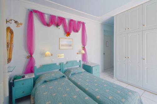 a bedroom with a blue bed and pink curtains at Villa Ianthia in Galaxidhion