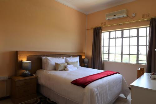 a bedroom with a white bed with a window and a bed sidx sidx at Sentosa Guest House in Francistown