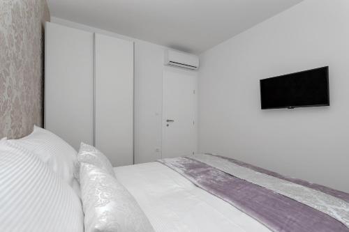 a white bedroom with a bed with a flat screen tv at Emilia Lofts in Tučepi