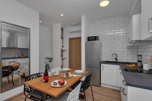 a kitchen with a wooden table and chairs in a kitchen at Emilia Lofts in Tučepi