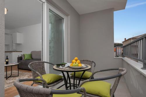 a balcony with chairs and a table with fruit on it at Emilia Lofts in Tučepi