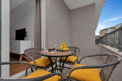 a balcony with a table with chairs and a bowl of fruit at Emilia Lofts in Tučepi