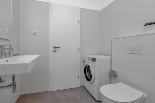 a white bathroom with a washing machine and a sink at Emilia Lofts in Tučepi