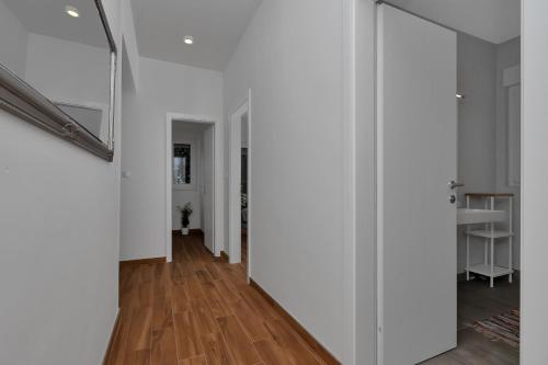 a hallway with white walls and wood floors and a mirror at Emilia Lofts in Tučepi