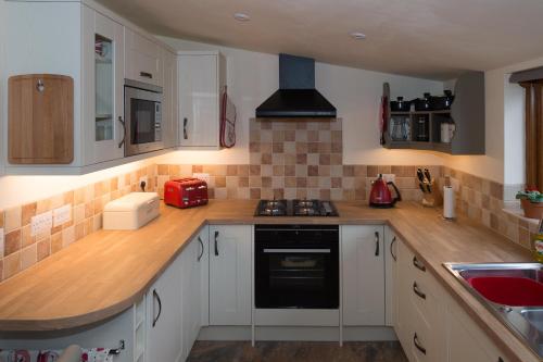 a kitchen with white cabinets and a stove top oven at The Old Cowstall in Somerton