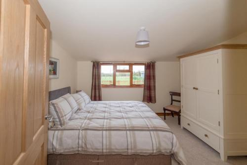 Un dormitorio con una cama grande y una ventana en The Old Cowstall, en Somerton