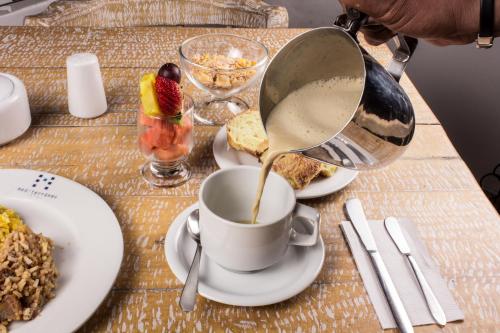 a person is pouring coffee into a cup on a table at Hotel Mediterraneo in Medellín