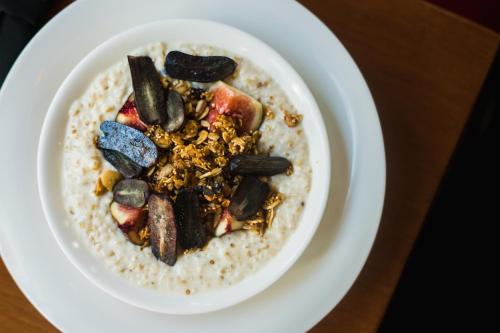 a white plate of oatmeal with vegetables on top at The Box House Hotel in Brooklyn
