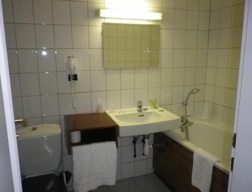 a bathroom with a sink and a tub and a toilet at Hôtel des Vosges 5 rue de la gare in Obernai