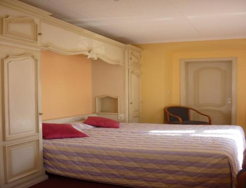 a bedroom with a bed with two red pillows on it at Hôtel des Vosges 5 rue de la gare in Obernai
